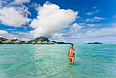 French Polynesia, Tahiti, Bora Bora, Woman in the ocean with bungalows in the background.