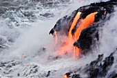 Hawaii, Big Island, near Kalapana, Pahoehoe lava flowing from Kilauea into frothy Pacific Ocean.