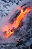 Hawaii, Big Island, near Kalapana, Pahoehoe lava flowing from Kilauea into frothy Pacific Ocean, Steam rising.