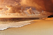 Hawaii, Oahu, North Shore, water lapping onto shore of a beautiful sandy beach at sunset.
