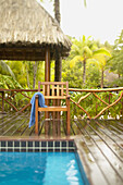 French Polynesia, Tahiti, Bora Bora, Deck chair with towel hanging over it next to swimming pool, tropical vegetation, selective focus