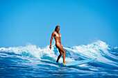 Hawaii, young Caucasian woman surfing wave in white bikini
