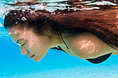 Hawaii, Big Island, Hapuna Bay, Young brunette woman swimming underwater.
