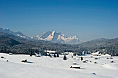 Schneebedeckte Hütten bei Mittenwald mit Zugspitze, Bayern, Deutschland