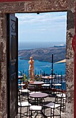 Looking down through doorway at romantic restaurant and the sea with statue in Santorini Greece in Greek Islands