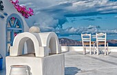 Postcard scene of two lonely chairs on terrace with table ready for tourists in Santorini Greece in Greek Islands