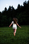 Junge Frau läuft über eine Wiese, Oberbayern, Deutschland