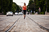 Young woman jogging over Maximilian bridge, Munich, Bavaria, Germany