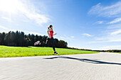 Joggerin läuft über Landstraße, Münsing, Bayern, Deutschland