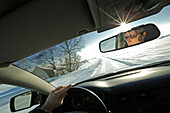 Man driving a car along a snow-covered street, Bavaria, Germany