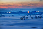 Blick auf winterliches Holzhausen mit Pfarrkirche St. Johann Baptist in der Abenddämmerung, Holzhausen, Münsing, Bayern, Deutschland