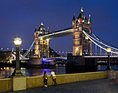 Zwei Frauen schauen auf Themse , Tower Bridge mit Beleuchtung in der Nacht, London, England