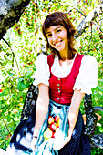 Frau sitzt in einem Apfelbaum, Steiermark, Österreich