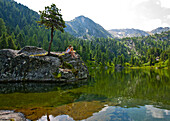 Young people sitting on a rock at lake Dieslingsee, Turracher Hoehe, Styria, Austria