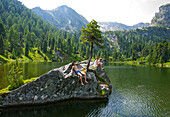 Young people sunbathing on a rock at lake Dieslingsee, Turracher Hoehe, Styria, Austria