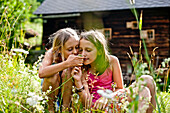 Zwei Mädchen riechen an einer Blume, Steiermark, Österreich