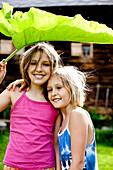 Two girls covering heads with a big leaf, Styria, Austria