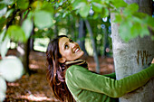 Junge Frau umarmt einen Baum, Steiermark, Österreich