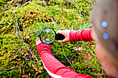 Mädchen betrachtet Pflanzen durch einen Lupe, Steiermark, Österreich