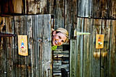 Young woman behind a ladies' room door looking at camera, lake Duisitzkar, Styria, Austria