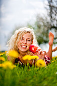 Young woman lying at a dandelion meadow, Stubenberg, Styria, Austria