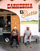 MEXICO, senior men sitting outside restaurant while one man reading newspaper, portrait