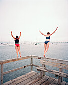 USA, Rhode island, rear view of women jumping off the pier into water