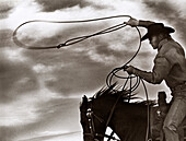 USA, California, Oxnard, Southern California, a cowboy swings his rope while running on horseback (B&W)