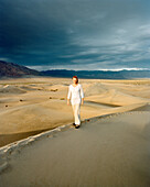 USA, California, young woman standing on sand dune, Stovepipe Wells, Death Valley National Park