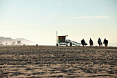 USA, California, Malibu, surfers walk across the sand towards the water at Zuma Beach