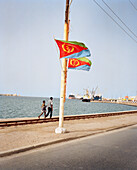ERITREA, Massawa, two men walk along the waterfront towards the Port of Massawa by the Red Sea