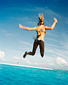 FIJI, Northern Lau Islands, a young woman jumps off of a the top of a yacht into the South Pacific Ocean