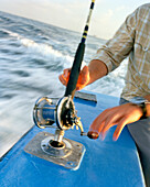 USA, Florida, man sitting on fishing boat preparing to reel in a fish, Destin