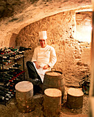 FRANCE, Auxerre, Yonne, Burgundy, portrait of chef Jean-Luc Barnabet sitting in wine cellar at his restaurant Jean-Luc Barnabet