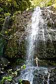USA, HAWAII, woman under Kalihiwai waterfall, Kauai