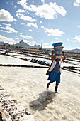 MAURITIUS, Tamarin, women carry heavy loads of salt to a storage facility where it is stored and prepared for transportation, Tamarin Salt Pans