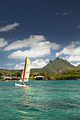 MAURITIUS, Trou D'eau Deuce, sailing in the Indian Ocean off the East coast of Mauritius with the 4 Sisters Mountains and the Four Seasons Resort in the background