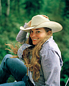 USA, Montana, portrait of a cowgirl in cowboy hat smiling, Mountain Sky Guest Ranch