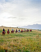 USA, Montana, cowboys and cowgirls riding horses back from a breakfast ride, Mountain Sky Guest Ranch