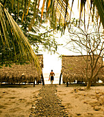 NICARAGUA, San Juan Del Sur, a man walks to the beach with his fins at Morgan's Rock Lodge, Morgan's Rock