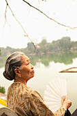 VIETNAM, Hanoi, portrait of a woman with a fan by Hoan Kiem Lake