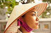 VIETNAM, Hanoi, portrait of a young woman wearing a non la or leaf hat, Hoan Kiem Lake