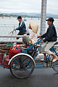 VIETNAM, Hue, a food vendor bicycles his wife across the Perfume river in the early morning