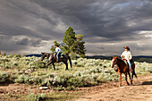 USA, Wyoming, Encampment, a man and woman ride horses under a dramatic sky, Abara Ranch