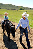 USA, Wyoming, Encampment, a wrangler leads a young boy on a pony, AbarA Ranch