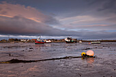 Sunrise over the port of Lindisfarne with boats lying on the mud flat at low tide, Lindisfarne, Holy Island, Northumberland, England, United Kingdom