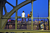 People sitting on the Hacker bridge in the evening, Munich, Bavaria, Germany