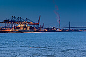 Container ship in front of a container bridge in winter, Altenwerder, Hamburg, Germany