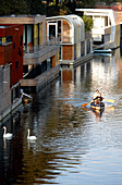 Couple canoeing on Eilbek canal along houseboats, Hamburg, Germany