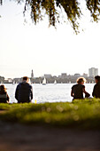 People sitting on a seawall at Outer Alster Lake, Hamburg, Germany